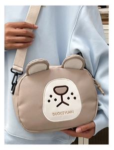 Detailed view of beige cartoon bear canvas crossbody bag with cute embroidery and strap