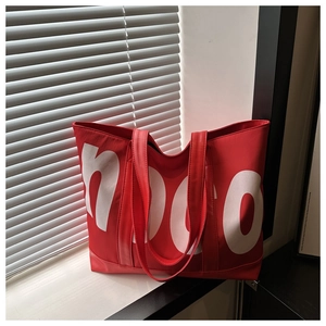 Dettaglio della borsa tote in ecopelle rossa con scritte bianche e ombre di luce soffusa