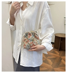 Detailed view of floral embroidered bucket bag with drawstring closure on model