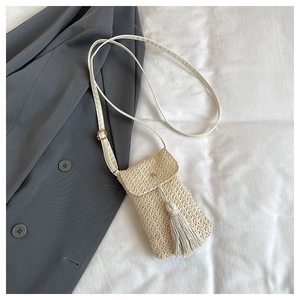 Texture détaillée en paille d'un mini sac bandoulière crème avec un gland élégant