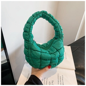Detail of green quilted puffer handbag with checkered pattern and ring handle