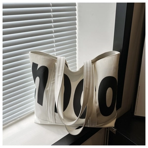 Dettaglio della grande borsa tote bianca in pelle con scritte HOOC su un davanzale soleggiato