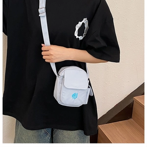 Nahaufnahme einer hellblauen Nylon-Umhängetasche mit Stickerei-Logo und verstellbarem Gurt