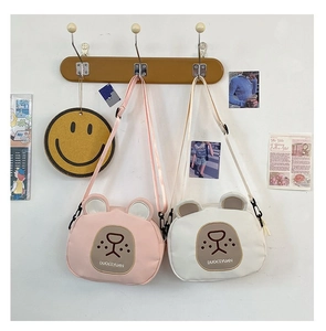 Detail of cute cartoon bear crossbody bags in pink and white with adjustable straps