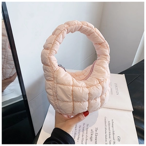 Close-up of peach pink quilted cloud handbag with soft padded texture and hobo style