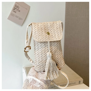 Détail du petit sac bandoulière en paille tressée avec de longues franges et boucle dorée