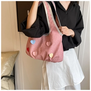 Detailed shot of a pink textured tote bag with colorful 3D hearts and silver faux leather trim
