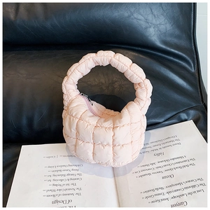Detailed view of pink quilted puffer handbag with soft fabric texture on a fashion magazine