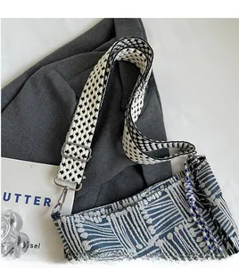 Detail of adjustable woven strap and silver metal hardware on striped canvas crossbody bag