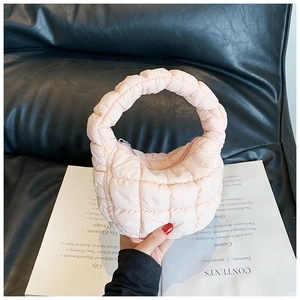 Detail of light pink quilted cloud bag with puffy texture and soft circular handles