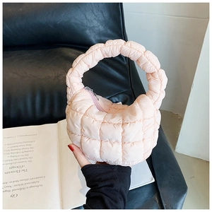 Detail of a pink quilted puffer bag with a semicircular design and silver zipper closure