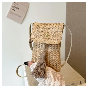 Détail du sac de téléphone en paille tissée avec boucle dorée et longues franges de glands