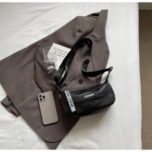 Détail du sac à main en cuir grainé noir avec étiquette FASHION et bandoulière