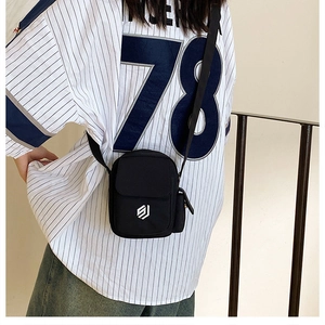 Seitenansicht einer schwarzen Mini-Umhängetasche aus Nylon mit Logo an einem Model