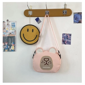 Detail of cute pink cartoon bear crossbody bag with adjustable strap on wooden hanger