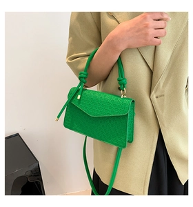 Detail view of emerald green shoulder bag with geometric texture and knotted strap design
