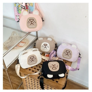 Detail shot of five cartoon bear crossbody bags in pink, white, black, purple, and khaki