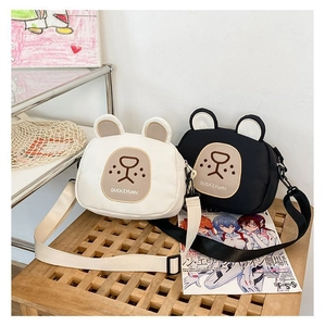 Detail of cute cartoon bear canvas crossbody bags in black and white with wide straps