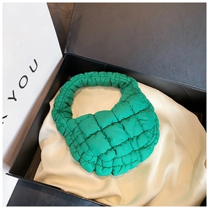Detail of a bright green quilted bubble handbag displayed in a premium black gift box