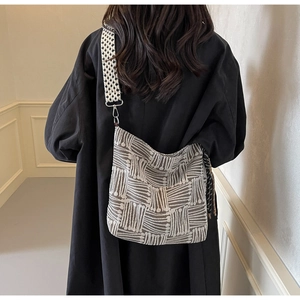 Macro detail of large capacity canvas crossbody bag with grey striped geometric patterns