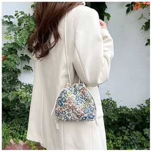 Detail of floral embroidery and woven drawstring on a vintage canvas bucket bag
