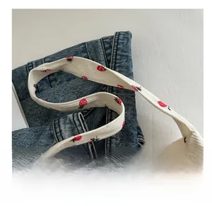 Détail des larges poignées confort sur le sac fourre-tout en velours côtelé blanc