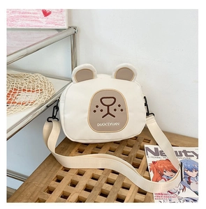 Close-up of cute cream-colored bear-shaped canvas crossbody bag on a wooden bench