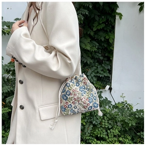 Detail of vintage bucket bag with floral embroidery and white cotton drawstring strap