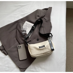 Sac à bandoulière crème avec texture litchi et sangle noire réglable sur fond élégant