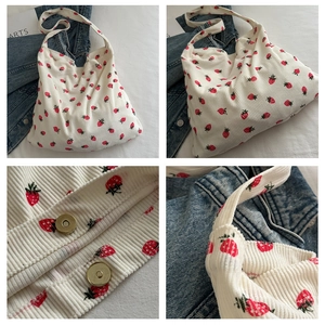 Detalle del bolso tote de pana blanca con estampado de fresas y cierre metálico imantado