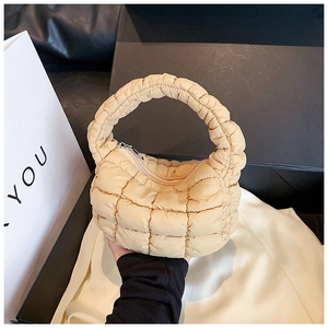 Detail of apricot quilted cloud bag featuring pleated handle and smooth zipper closure