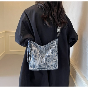 Detail of blue and white striped canvas crossbody bag with decorative side tassels