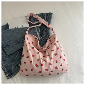 Détail de la texture en velours côtelé rose avec imprimé fraise sur le grand sac cabas