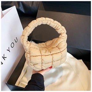 Detail of beige quilted puff bag texture and round handle inside a premium black gift box