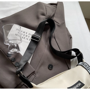 Détail du sac crème avec étiquette FASHION et bandoulière noire avec logo FEMME
