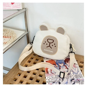 Close-up of white canvas bear crossbody bag showing texture and adjustable strap details