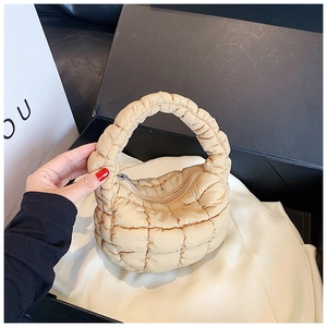 Detailed close-up of beige quilted cloud bag with zip closure on black gift box