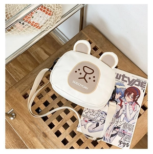 Detailed macro shot of white canvas crossbody bag featuring cute 3D bear ears and cartoon face