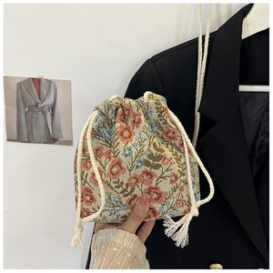 Detailed close-up of floral embroidery and drawstring tassels on a bucket bag