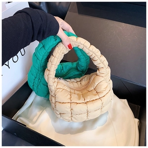 Detailed macro view of beige and green mini puffer bags with quilted nylon fabric texture