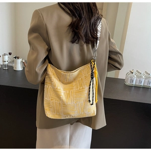 Detailed back view of a large yellow striped canvas hobo bag with woven strap and charm