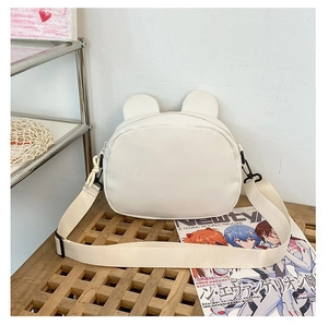 Detail showing the white cartoon bear crossbody bag with a wide fabric shoulder strap