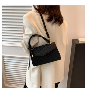 Detail of knot handle on black geometric embossed square bag with gold metal hardware