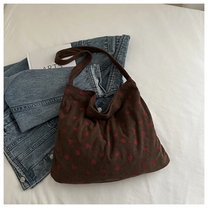 Détail de texture du sac cabas en velours côtelé marron avec motifs de cœurs rouges