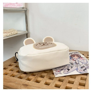 Detail of white canvas bear bag showing 3D ears and brown embroidered bear face