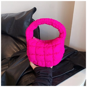 Close-up of fuchsia puffy quilted handbag with integrated ring handle and metal zipper