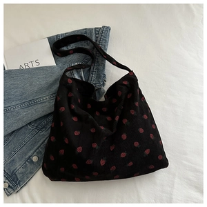 Détail du sac cabas en velours côtelé noir avec motif fraise rouge sur tissu