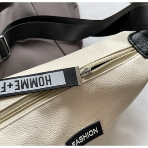 Détail du sac beige en similicuir grainé avec fermeture éclair argentée et sangle tissée