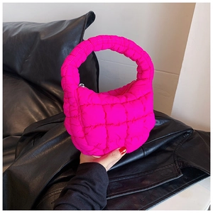 Detail of bright pink quilted cloud bag with puffy grid texture and curved handle