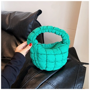 Detail of green quilted puffer handbag featuring soft padded texture and grid pattern